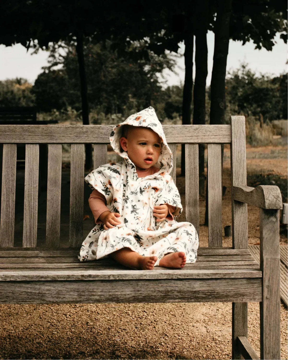 child wearing a beach poncho on a bench