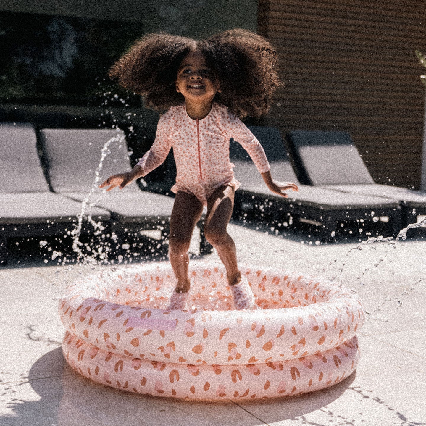 child splashing the water in a kids pool