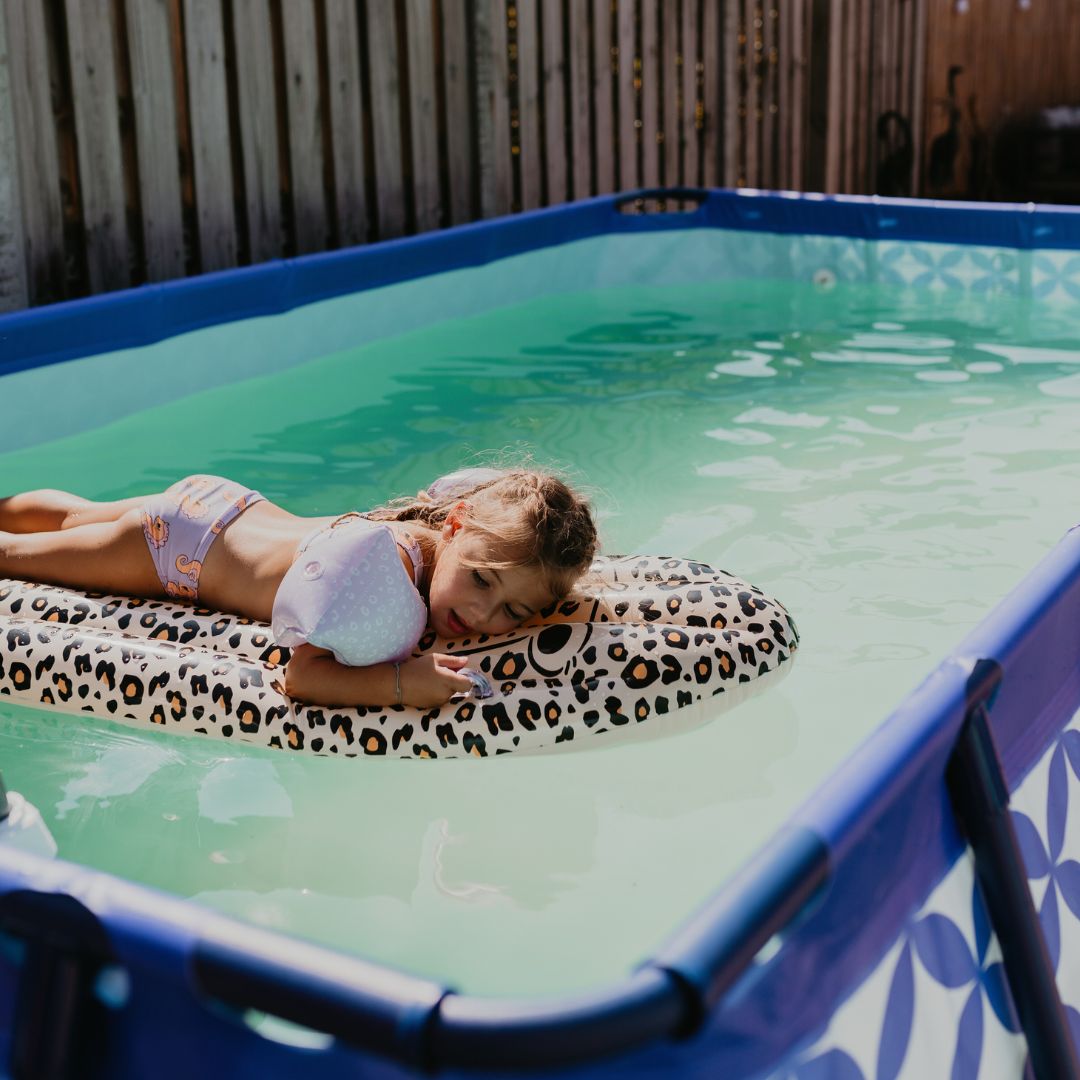 child laying on surfboard in pool