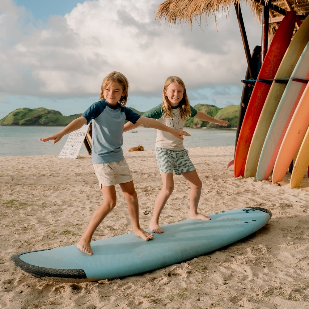 children standing on surfboard on the beach